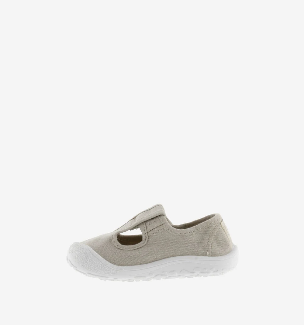 Sapato infantil de tecido bege claro com sola branca e fecho de velcro.