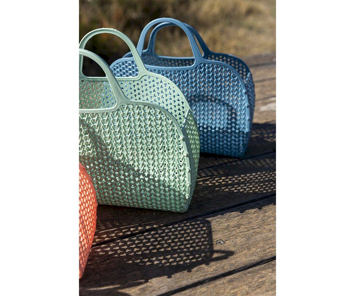 Três malas de mão plásticas coloridas em piso de madeira ao ar livre