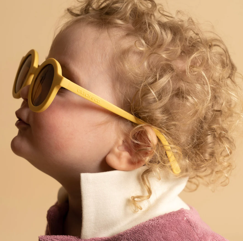 Criança com óculos de sol amarelos com armação redonda