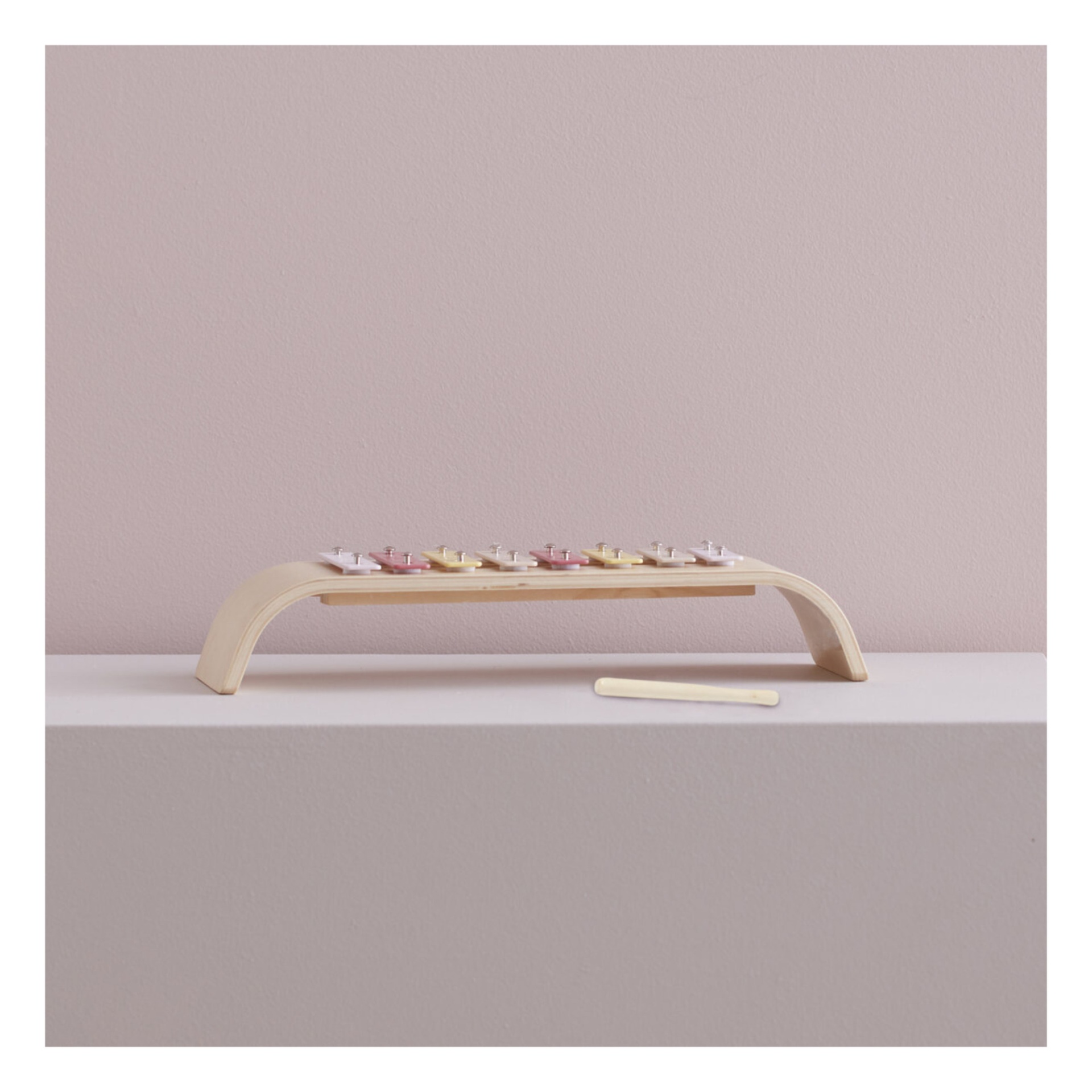 Xilofone colorido em madeira com martelo numa superfície branca