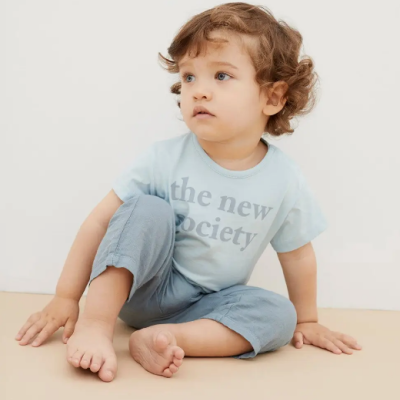 Criança sentada no chão com t-shirt azul clara e calças azuis