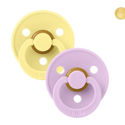 Duas chupetas redondas de silicone, uma amarela e outra rosa, com alças e orifícios.