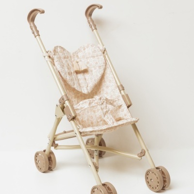 Carrinho de boneca bege com padrão floral, rodas e alças curvas.