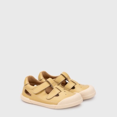 Sapatos infantis amarelos com fecho de velcro em fundo cinzento