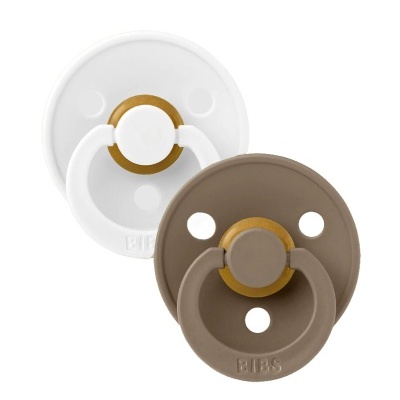 Duas chupetas BIBS, uma branca e uma castanha, com detalhes dourados.