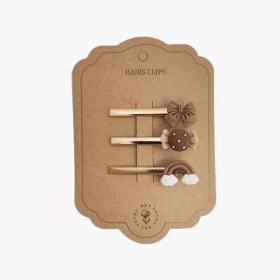 Conjunto de três presilhas de cabelo castanhas e bege com decorações variadas em cartão castanho.