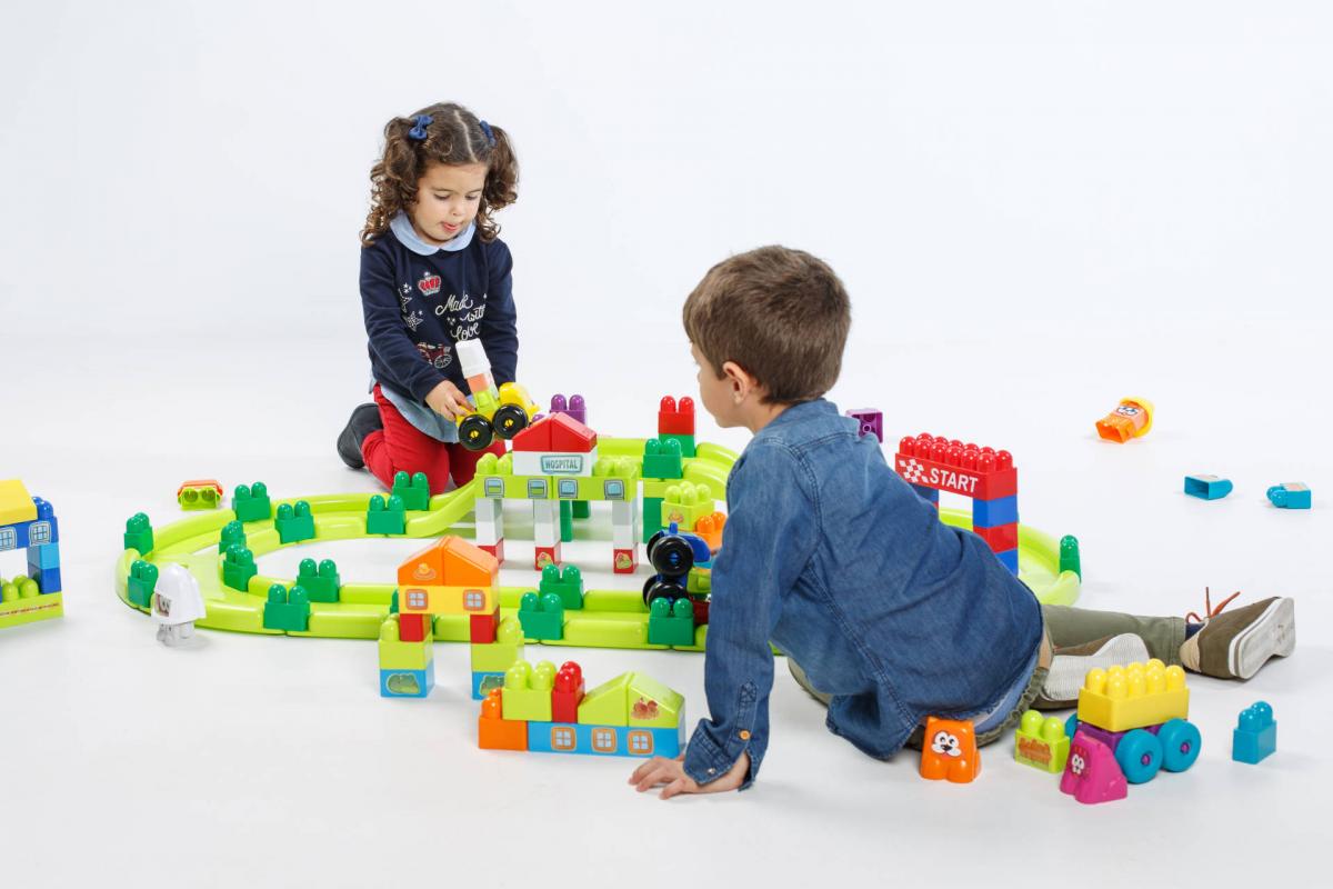 Super Blocos de Pista de Corrida 70pcs +18 meses 32345 Miniland Crianças a brincar com blocos de construção coloridos no chão branco