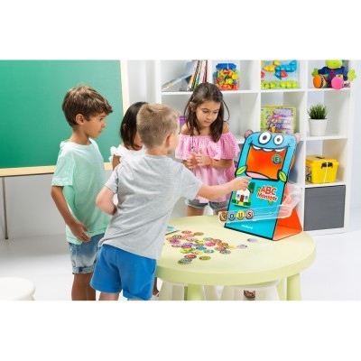 Crianças a jogar com brinquedo educativo ABC Monster numa mesa redonda branca