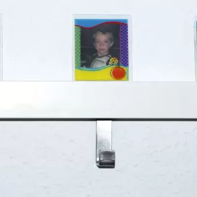 Três molduras de fotos com crianças penduradas acima de ganchos metálicos