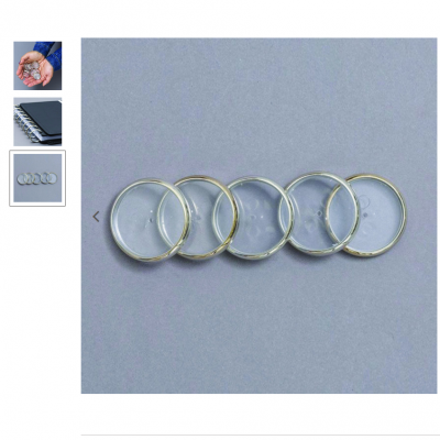 Cinco argolas metálicas prateadas alinhadas sobre fundo cinza