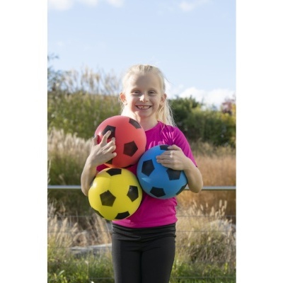 Menina com bolas de futebol de espuma coloridas ao ar livre