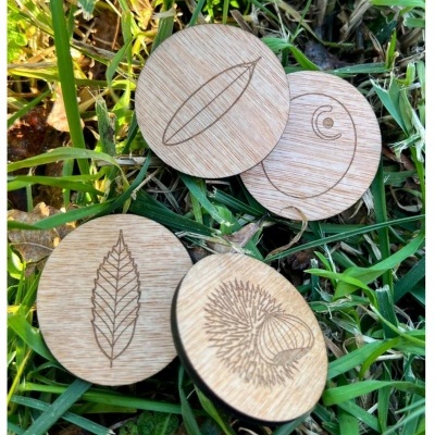 Discos redondos de madeira gravados com desenhos naturais sobre relva.