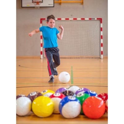 Bola de futebol branca com o texto spokey e bolas coloridas em primeiro plano em quadra desportiva