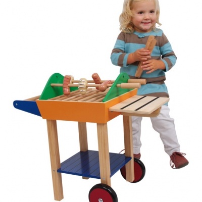 Criança brinca com carrinho de cozinha de madeira colorido com utensílios de madeira