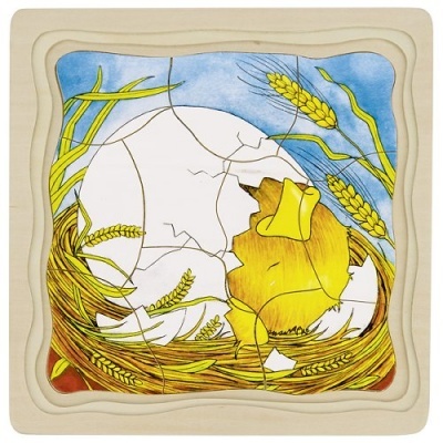 Quebra-cabeças de madeira com pintainho amarelo quebrando ovo branco em ninho com trigo