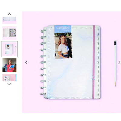 Caderno com capa branca marmoreada e elástico rosa junto a um lápis sobre fundo rosa.