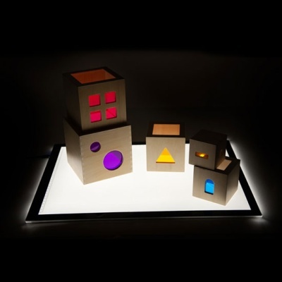 Caixas de madeira com recortes coloridos e iluminação em fundo escuro