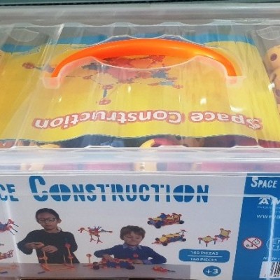 Caixa transparente com tampa laranja contendo brinquedo de construção 'Space Construction'.