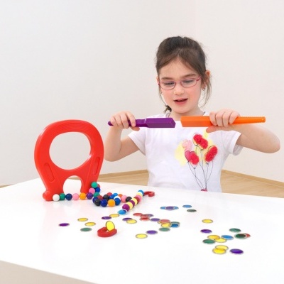 Criança a brincar com brinquedo magnético colorido numa mesa branca