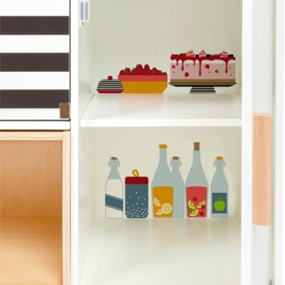 Armário branco aberto com saladeira, bolo e ilustrações de garrafas; painel superior com texto '-18°'