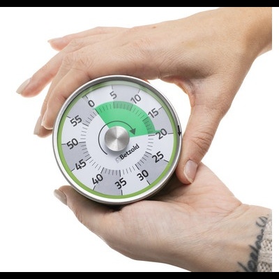 Temporizador mecânico redondo verde e branco segurado por duas mãos