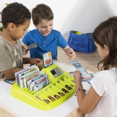 Crianças a brincar com caixa registadora de brinquedo numa mesa branca