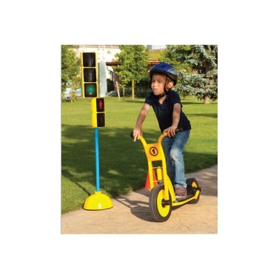 Criança a andar de trotinet elétrico amarelo junto a semáforo de brinquedo num parque.