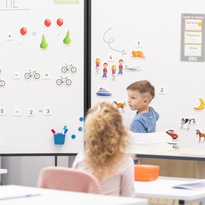 Sala de aula com quadro branco magnético com adesivos e crianças a interagir