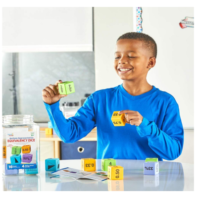 Menino a sorrir com dados coloridos de aprendizagem numa mesa branca em sala de aula