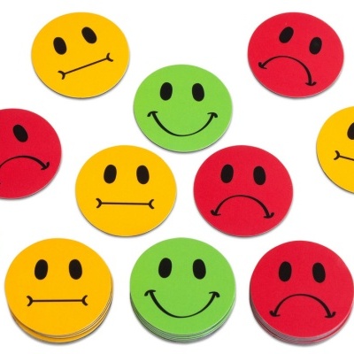 Círculos de papel coloridos com expressões faciais variadas sobre fundo branco