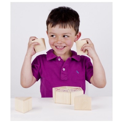 Menino com cubos de madeira na mão e mesa branca