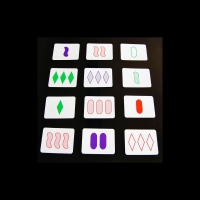 Cartas com formas geométricas em verde, vermelho e roxo sobre fundo preto