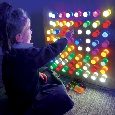 Criança com painel iluminado e pinos coloridos no chão