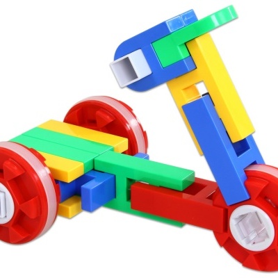 Brinquedo de construção plástico colorido formando um veículo com rodas vermelhas.
