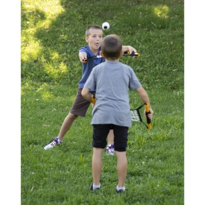 Duas crianças a jogar paddle num campo de relva verde.