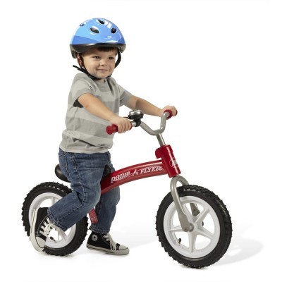 Criança com capacete azul numa bicicleta vermelha Radio Flyer sem pedais