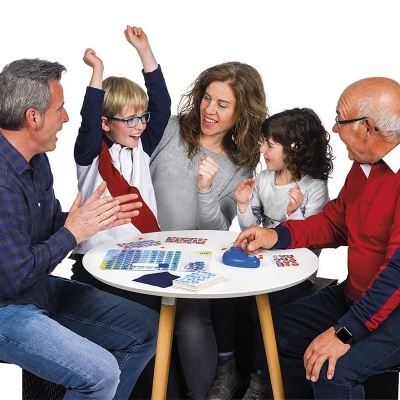 Família a jogar jogo de tabuleiro numa mesa redonda branca com peças azuis e cartas