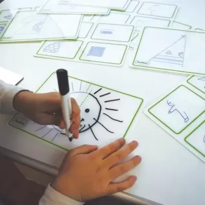 Mesa iluminada com cartas transparentes e desenho de sol feito a marcador