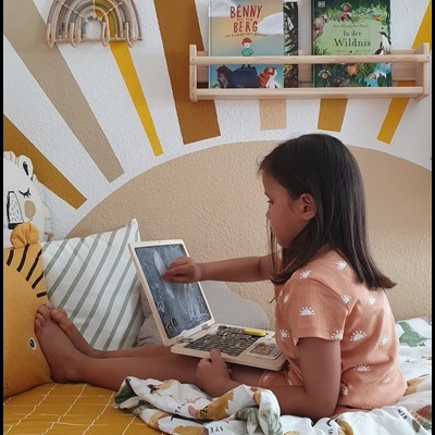 Criança sentada numa cama com decoração infantil e acessórios temáticos de dinossauros