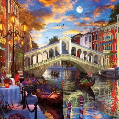 Cena de canal com ponte arqueada, gôndolas, edifícios coloridos e mesa de jantar exterior com toalha branca e flores