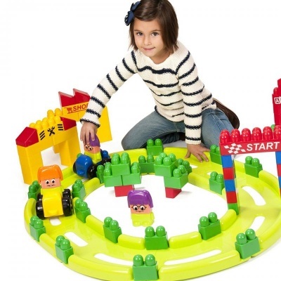 Menina a brincar com circuito de carrinhos de brinquedo colorido