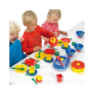 Crianças a brincar com utensílios de cozinha de plástico coloridos numa mesa branca.