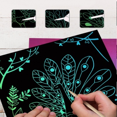 Folha preta com desenho de pavão e folhas sendo colorida por mãos com lápis de cor