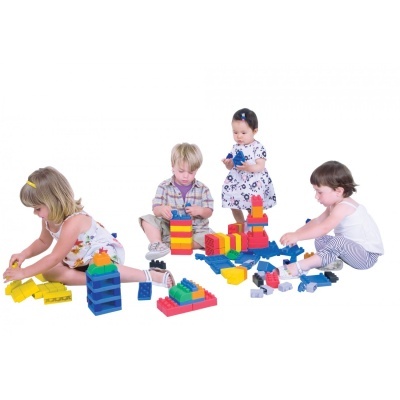Quatro crianças a brincar com blocos de construção grandes coloridos sobre fundo branco