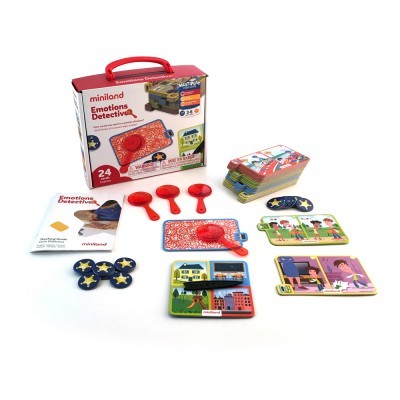 Jogo educativo Miniland Emotions Detective com cartas, loupe e fichas em fundo branco.