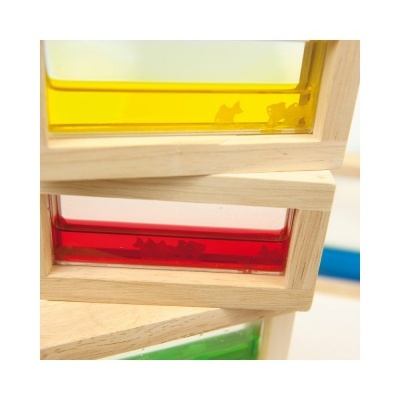 Três blocos de madeira com painéis coloridos amarelo, vermelho e verde e objetos pequenos no interior