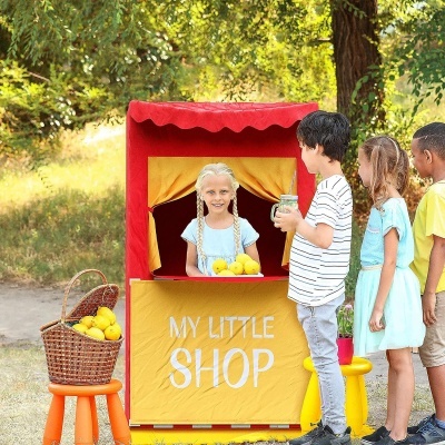 Banca infantil vermelha e amarela com limões e crianças à volta