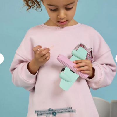 Criança com camisola rosa claro segura brinquedo avião em tons pastel verde-água e rosa