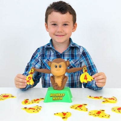 Criança segura peças de jogo de bananas com números, macaco e base verde MONKEY MATH