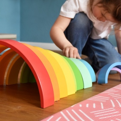Arcos de madeira coloridos em sequência no chão com criança a brincar